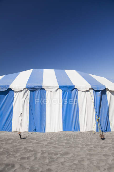 A large blue and white striped tent or marquee on a beach — Foto stock