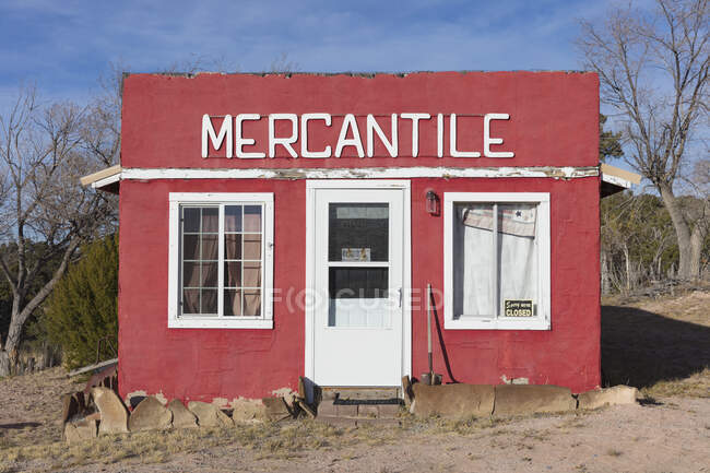 A red painted building frontage, with a sign MERCANTILE, windows boarded up. — Fotografia de Stock