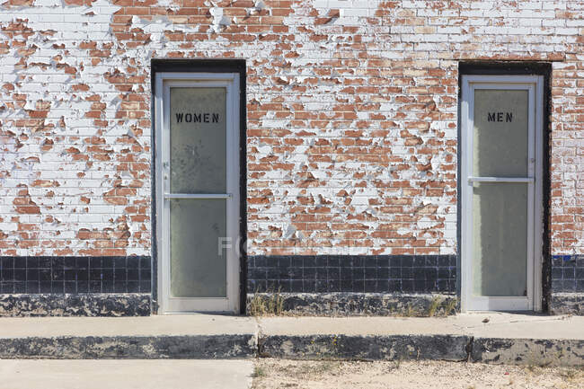 Un edificio con dos puertas, etiquetadas Mujeres y Hombres, baños. - foto de stock