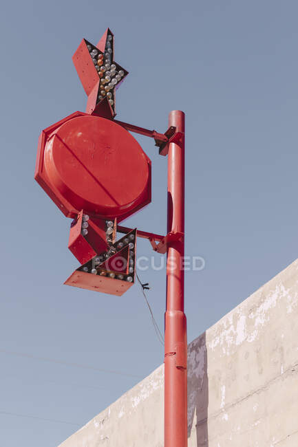 An advertising sign with arrows and lights on a post against blue sky. — Foto stock