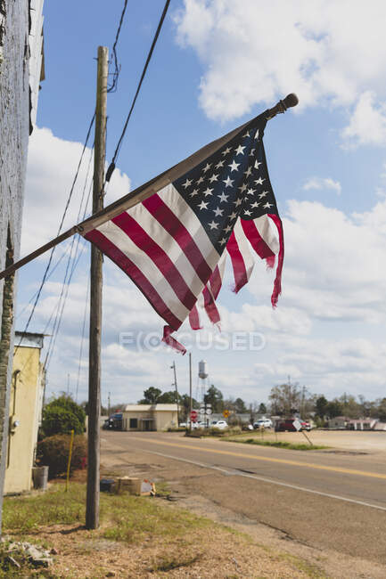 Tattered American flag flying on a building on Main Street. — Stock Photo