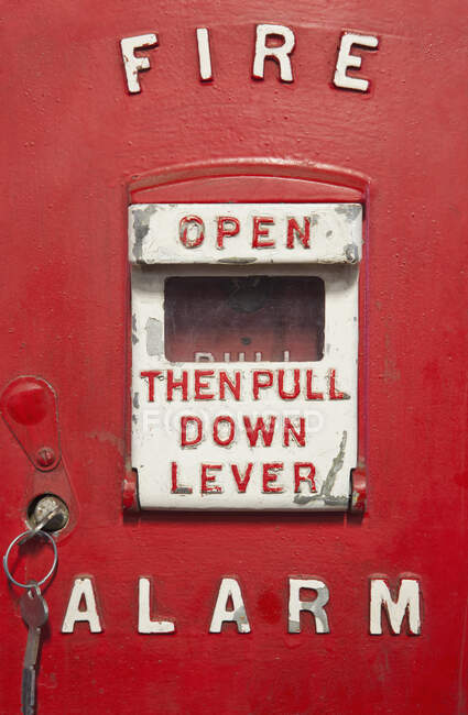 Una caja de alarma de incendio antigua de metal rojo. Una palanca de alarma con instrucción escrita - foto de stock