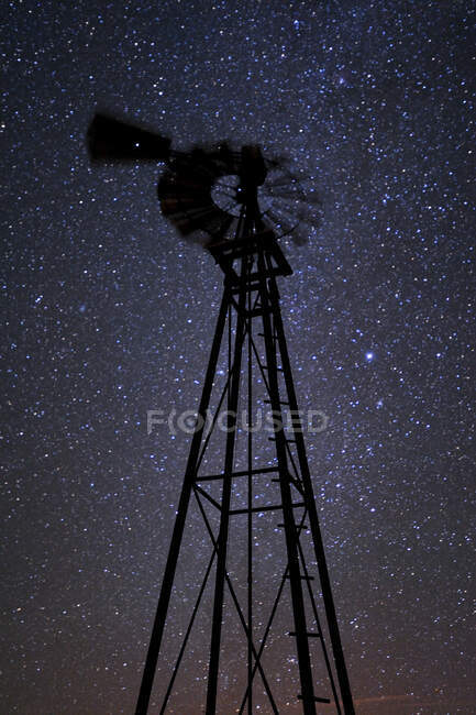 A windmill tower at night, against a starry sky, low angle view. — Photo de stock
