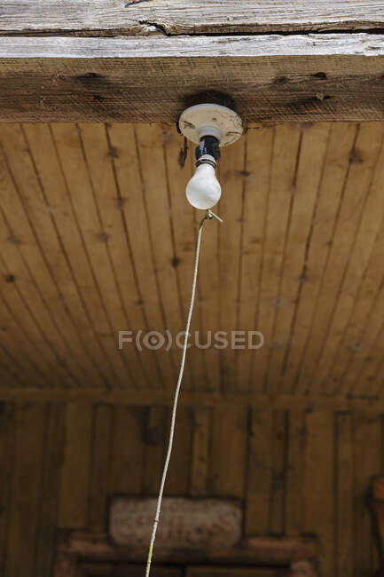Old incandescent light bulb on a porch beam with a string pull control — Stock Photo