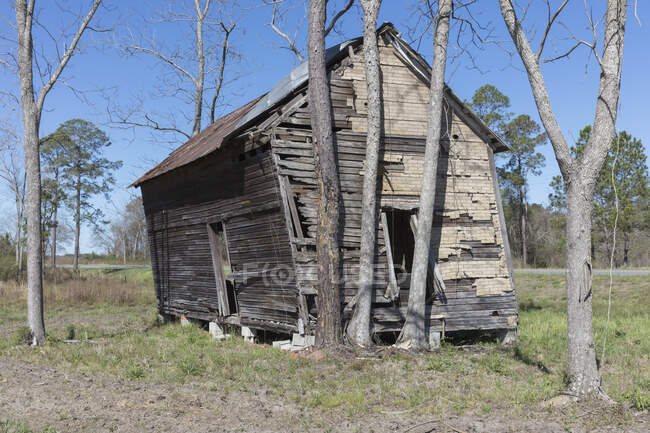 Casa abandonada, una pequeña cabaña de madera, un edificio inclinado hacia un lado. - foto de stock
