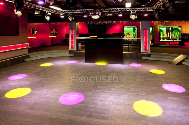 Empty nightclub, coloured lights and spots, screens and DJ decks. — Stock Photo