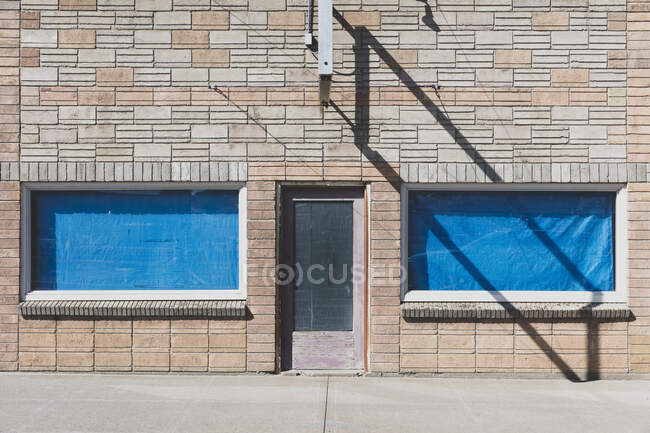 Empty building with covered windows, and an empty sign frame. — Foto stock