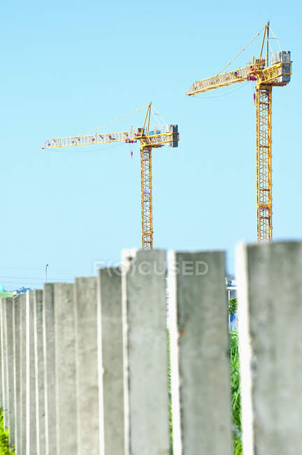Deux grues de construction au-dessus d'une rangée de piliers en béton — Photo de stock