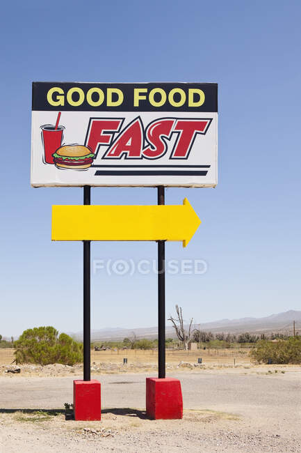 Fast food sign by the road, Good Food Fast and a yellow arrow. — Photo de stock