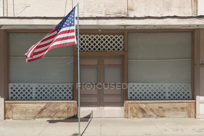 Bandera americana volando fuera de un edificio en una calle principal. - foto de stock