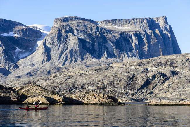 Two kayakers on the water off the rocky shore, Greenland. — Stock Photo