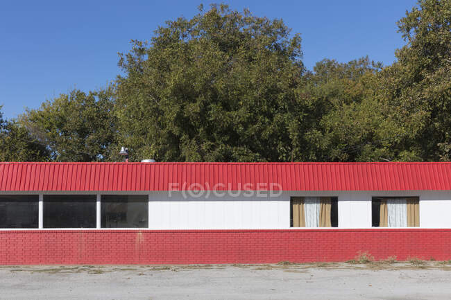 Edificio vacío junto a la carretera rojo y blanco con ventanas tapiadas. - foto de stock