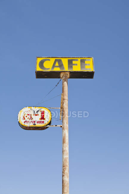 Cafe sign, rusted and faded, on a pole, blue sky background. — Fotografia de Stock