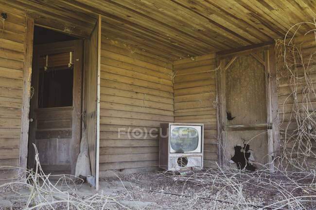 Old TV set on front porch of an abandoned homestead. — Stockfoto
