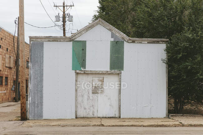 A small metal building boarded up on a sideway in a small town. - foto de stock