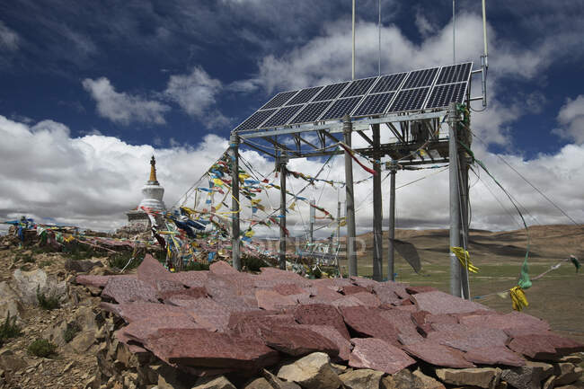 Una torre del telefono cellulare solare commerciale, mani pietre e bandiere di preghiera e un piccolo stupa o tempio buddista — Foto stock
