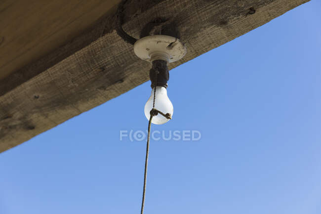 Old incandescent light bulb on a porch beam with a string pull control. — Fotografia de Stock
