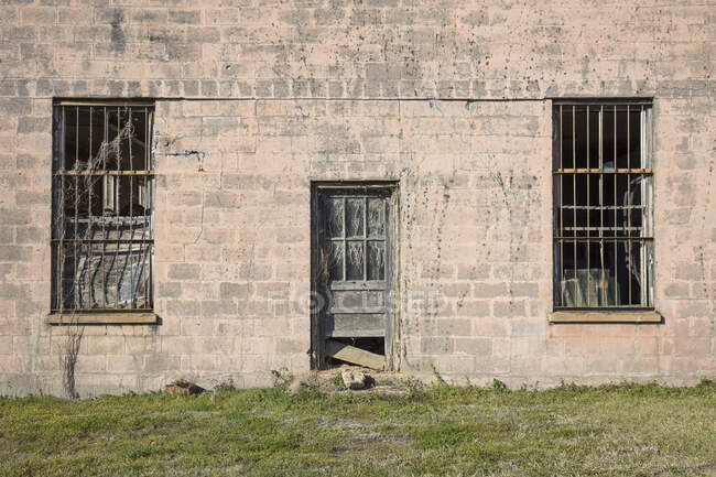 Façade de prison abandonnée, un bâtiment vide avec barbecue les fenêtres. — Photo de stock