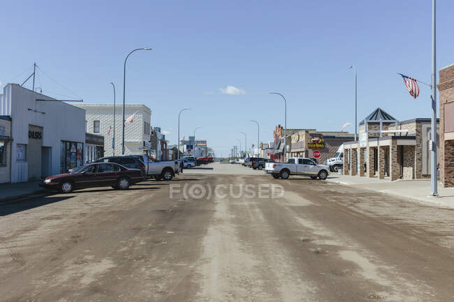 Main Street,  rows of small buildings, stores and businesses, flying American flags, parked trucks and cars. - foto de stock