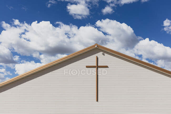 Uma grande cruz na parede exterior de uma igreja em uma pequena cidade. — Fotografia de Stock