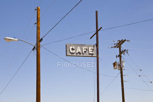 Cafe-Schild hoch oben auf einem Mast, Strom- und Telefonverkabelung an Pfosten. — Stockfoto
