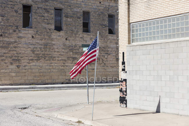 American flag flying outside a building on a main street. — Fotografia de Stock