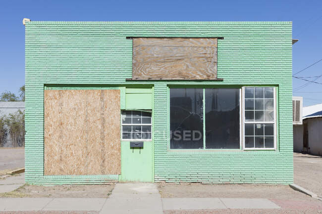 Abandoned roadside store in a small town, boarded up window, green painted exterior. — Fotografia de Stock