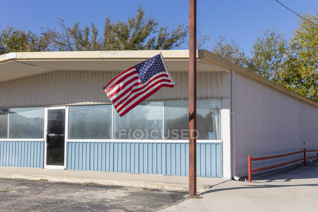 American flag flying outside a building on a main street. — Fotografia de Stock