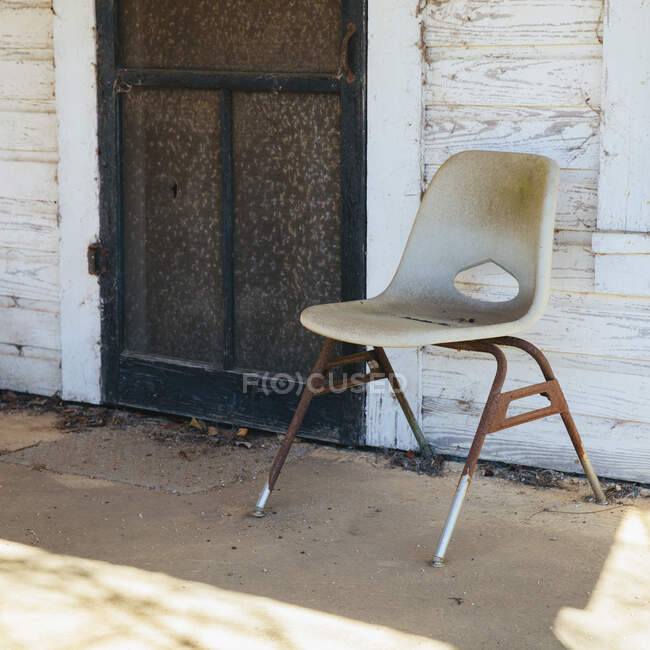 Chair on the porch by a door of old building. — Stock Photo