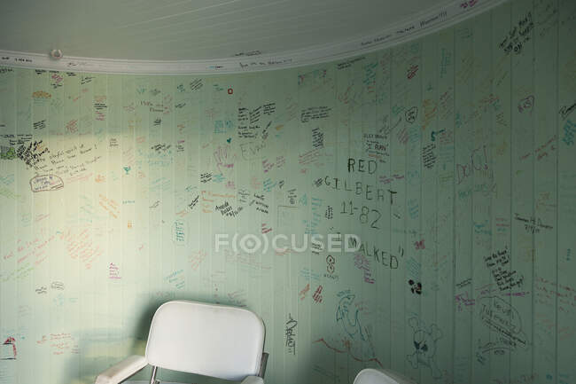 Die Graffiti an den Wänden eines Leuchtturms, ein leerer Raum mit Stuhl, Zeichnungen und Botschaften. — Stockfoto