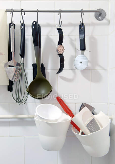 Orologio da polso appeso a un rack tra vari utensili da cucina — Foto stock