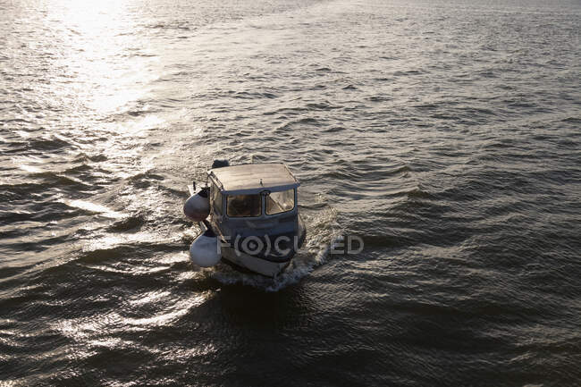 Un petit bateau de pêche sur la mer au coucher du soleil, vue surélevée. — Photo de stock