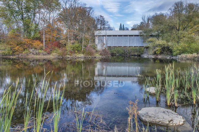 A covered bridge across a river in autumn. — Stock Photo