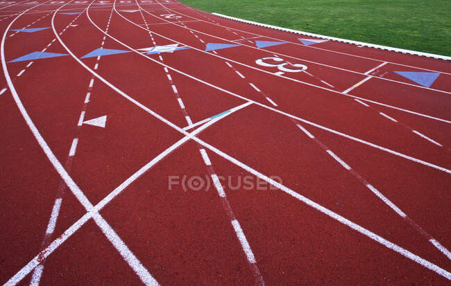 Красная искусственная беговая дорожка. Спортивная площадка. Покрашенные обозначенные линии для полос. — стоковое фото