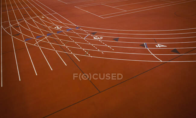 Una pista roja, campo de atletismo, una sección de esquina de pista marcada con carriles - foto de stock