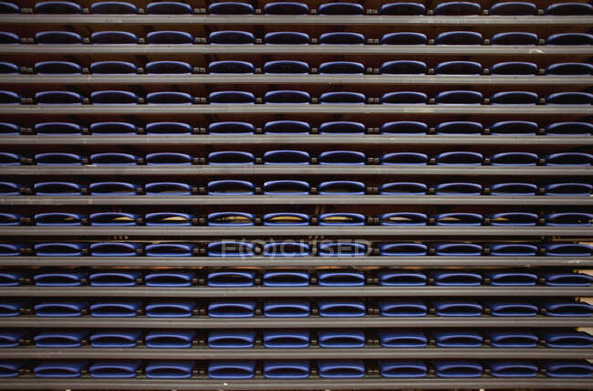 Una fila de asientos plegados en estantes en un recinto deportivo cubierto. - foto de stock