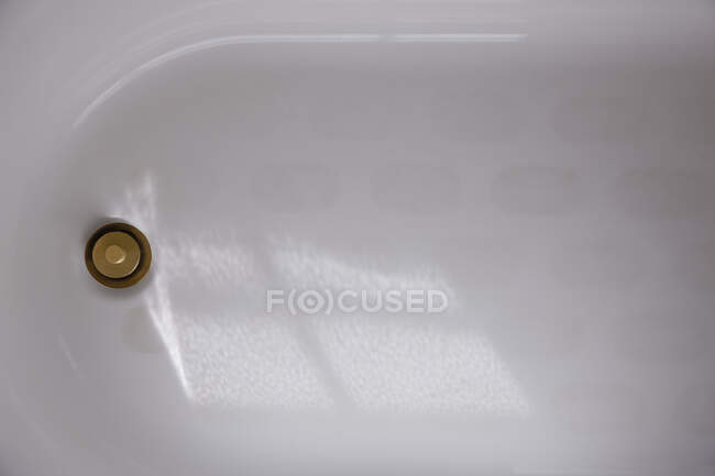 Uma banheira de esmalte branco com um plugue de latão ou tampa de drenagem, vista aérea. — Fotografia de Stock