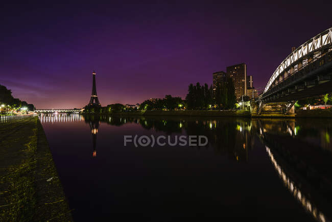 La ciudad por la noche, vista a lo largo del río Sena hasta el Tour Eiffel, edificios y carreteras iluminadas. - foto de stock
