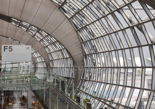 Вылет ворот в аэропорту Бангкока, возвышенный вид на изогнутую стеклянную стену терминала и зону ожидания. — стоковое фото