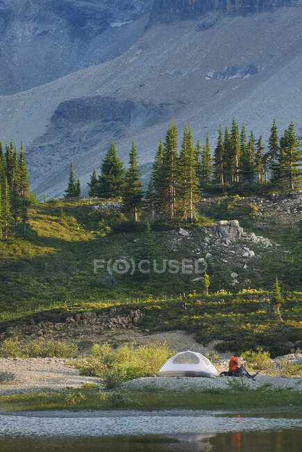 Una piccola tenda bianca e uno zaino sulle rive di un lago nel Parco Nazionale Yoho. — Foto stock