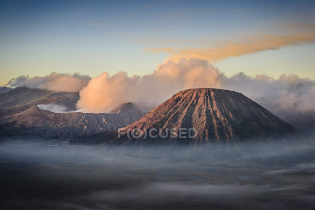 Der Vulkan Mount Bromo, ein Somma-Vulkan und Teil des Tengger-Gebirges, dessen Kegel über dem Nebel in der Landschaft aufragt. — Stockfoto