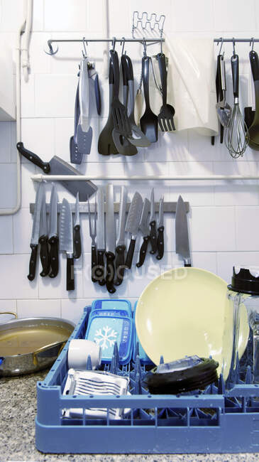 Una cocina con platos en un estante y almacenamiento colgante de cuchillos y utensilios de cocina - foto de stock