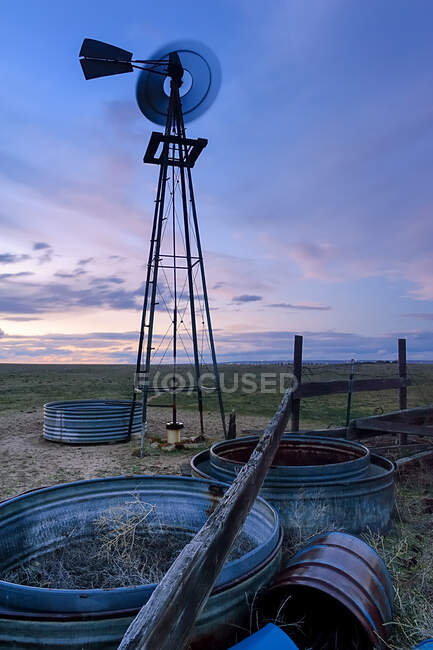 A spinning windmill metal wheel and wind tower, blurred motion, at sunset on the prairie or high plains of Colorado. — Stock Photo