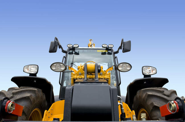 Una vista frontal de un nuevo vehículo excavador de tierra moderno con pintura amarilla y una cabina de conductor. - foto de stock