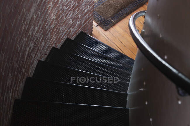 Escaleras de caracol, una escalera con una barandilla girando y girando en un pequeño espacio, una pared de ladrillo. - foto de stock