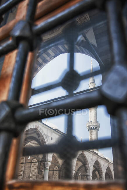 Istanbul city, a landmark, a tall minaret and arches with stonework and fretwork detail, and view through metal gates o bars. — Stock Photo