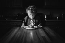 Menino soprando uma vela no donut de aniversário — Fotografia de Stock