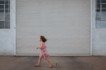 Fille en robe rose marchant dans la rue — Photo de stock