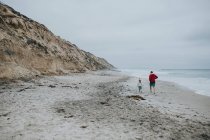 Padre con su hija caminando en la playa de arena - foto de stock
