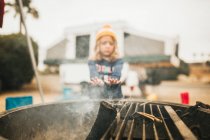 Girl warming her hands near the grill — Stock Photo